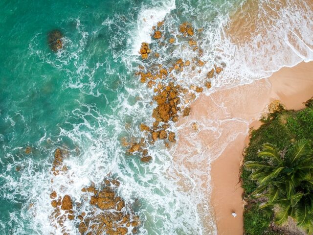Descubra as 10 melhores praias do Brasil para suas férias Stunning aerial view of a tropical beach with waves breaking on the sandy shore in Brazil.