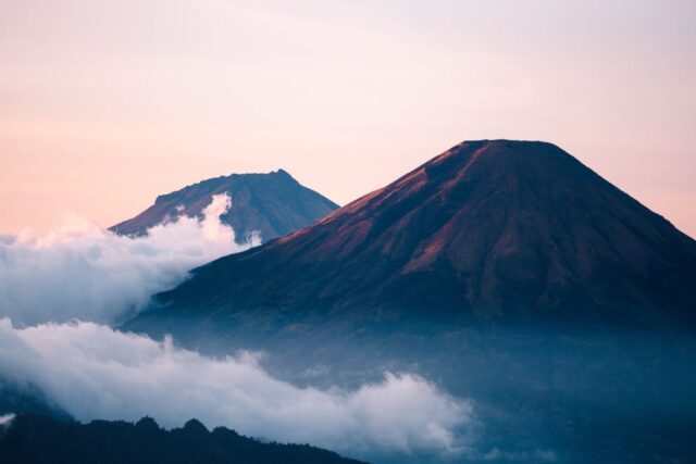 Roteiro de aventura pelos vulcões da Indonésia: explore já! Capture of Mount Sumbing in Indonesia during sunrise with misty clouds and vibrant colors.